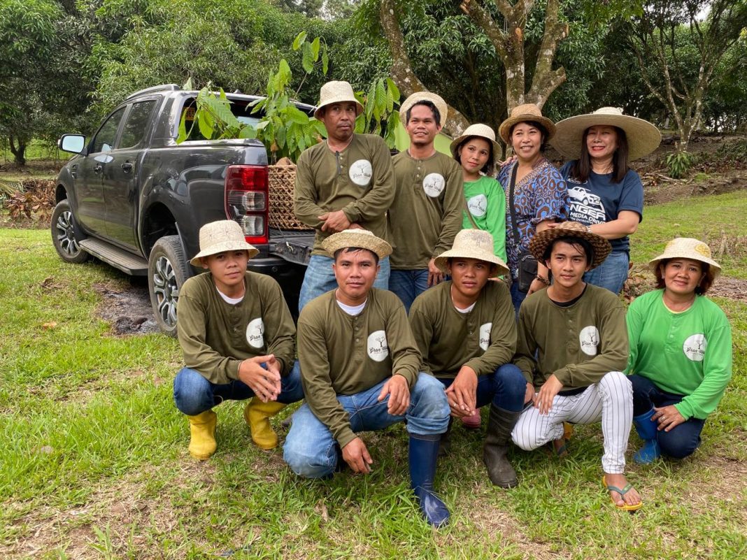 Grand Verde’s Wit Holganza and PRWorks’ Doris Mongaya pose with farm workers behind a Ford Ranger after hauling in the cacao seedlings and fruit